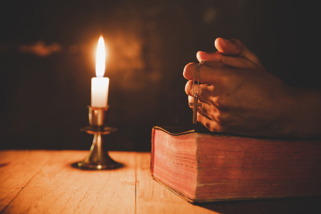 close up man s hand is praying church with lit candle